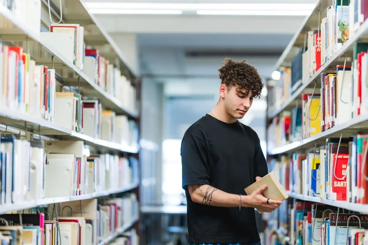 Étudiant qui prend un livre dans une allée de la bibliothèque