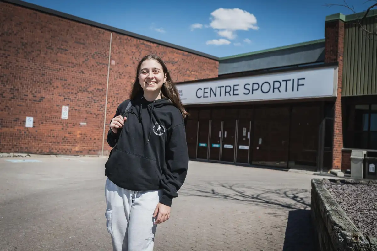 Étudiante devant l'entrée du Centre sportif